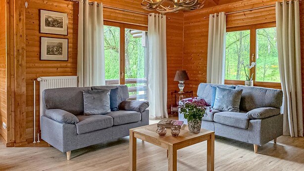 A cozy log cabin interior with two grey sofas, a wooden coffee table, and framed pictures on the walls. - Stunning home in Nimsreuland with WiFi (Nimsreuland)