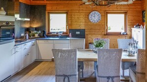 A cozy kitchen with wooden walls, a large clock, wicker chairs, and a rustic ceiling. - Stunning home in Nimsreuland with WiFi (Nimsreuland)