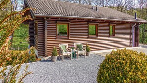 A log cabin with a tiled roof, a gravel driveway, and a small patio area with outdoor furniture. - Stunning home in Nimsreuland with WiFi (Nimsreuland)