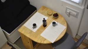 Een houten tafeltje met twee koffiekopjes, een koffiezetapparaat en een schaal kersen.