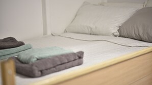 Een bed met een witte matras, een grijze kussen en een bruine kussen.