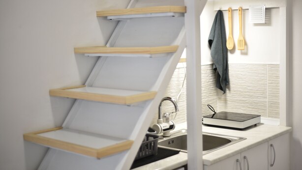 Een keuken met een houten wenteltrap, een spoelbak en een raam met een handdoek.