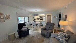 A living room with a dark blue armchair, a grey armchair, and a grey sofa with a blue patterned pillow. There is a wooden coffee table in the center. - Ocean Hideaway 111-Oceanfront 18th St, Free WiFi, Elev, W/D, AC (Ocean City)