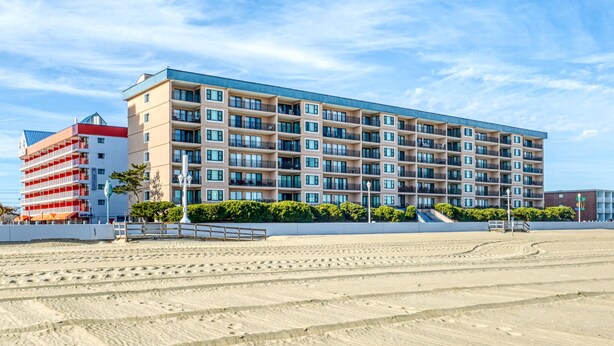 A multi-story hotel with balconies, located near a sandy beach. - Ocean Hideaway 111-Oceanfront 18th St, Free WiFi, Elev, W/D, AC (Ocean City)