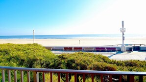A beach view from a balcony with a wooden deck, benches, and a street lamp. - Ocean Hideaway 111-Oceanfront 18th St, Free WiFi, Elev, W/D, AC (Ocean City)