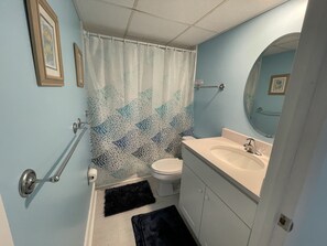 A bathroom with a toilet, sink, and shower curtain. - Ocean Hideaway 111-Oceanfront 18th St, Free WiFi, Elev, W/D, AC (Ocean City)