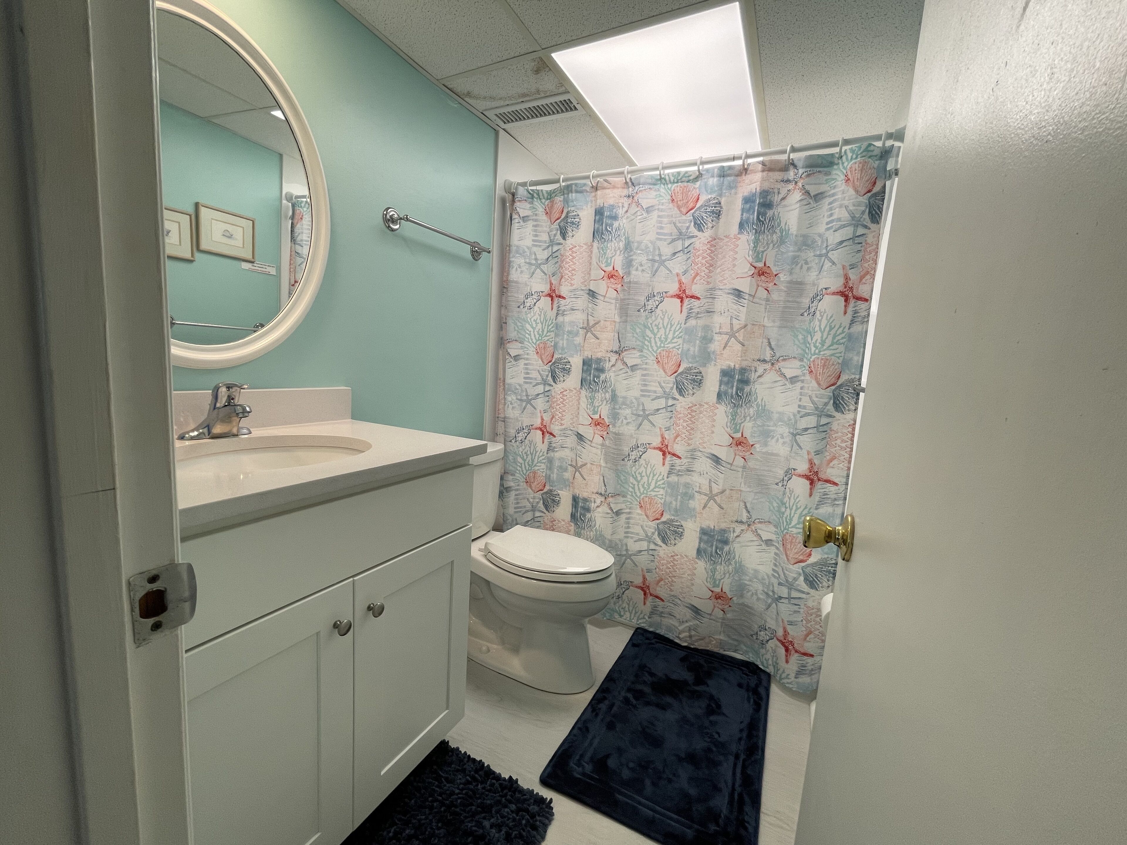 A bathroom with a white sink, a toilet, and a shower curtain with a floral pattern.