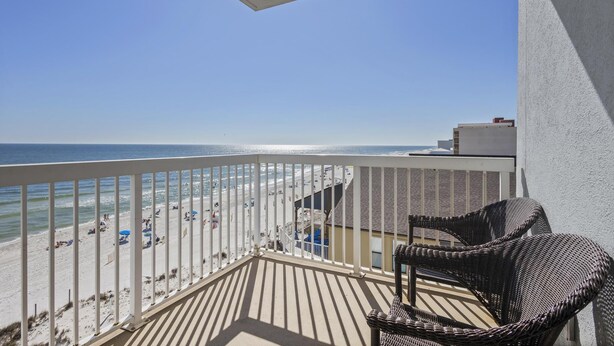 A balcony with wicker chairs overlooking a beach. - Dog friendly beachfront condo with sunset view (Gulf Shores)