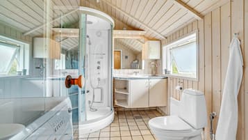 Et moderne badeværelse med en glasafskærmet brusekabine, et hvidt toilet og en vask.