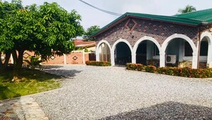 A building with a brick facade, a green roof, and a gravel driveway. - Cosy Rooms Away in a Stunning House (Koforidua)