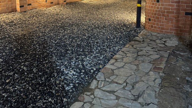 A paved pathway with a brick wall on one side and a stone wall on the other, leading to a building entrance. - Cosy Rooms Away in a Stunning House (Koforidua)