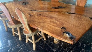 A large wooden dining table with a natural wood finish and visible grain patterns, surrounded by four wooden chairs with curved backs. - Cosy Rooms Away in a Stunning House (Koforidua)