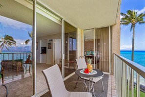 A balcony with a table, chairs, and a pineapple centerpiece.
