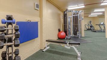 Een sportschool met gewichthefapparatuur, een bank, een rode fitnessbal en cardio-apparaten.