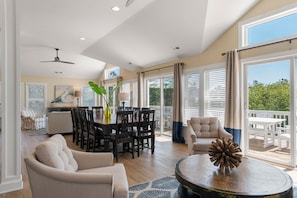 A spacious living room with a dining area, large windows, and a balcony.