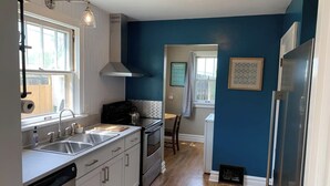 Una cocina moderna con armarios blancos, electrodomésticos de acero inoxidable y una pared azul de acento.
