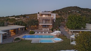 Uma casa moderna de dois andares com piscina, área de estar ao ar livre e vista para uma paisagem montanhosa.