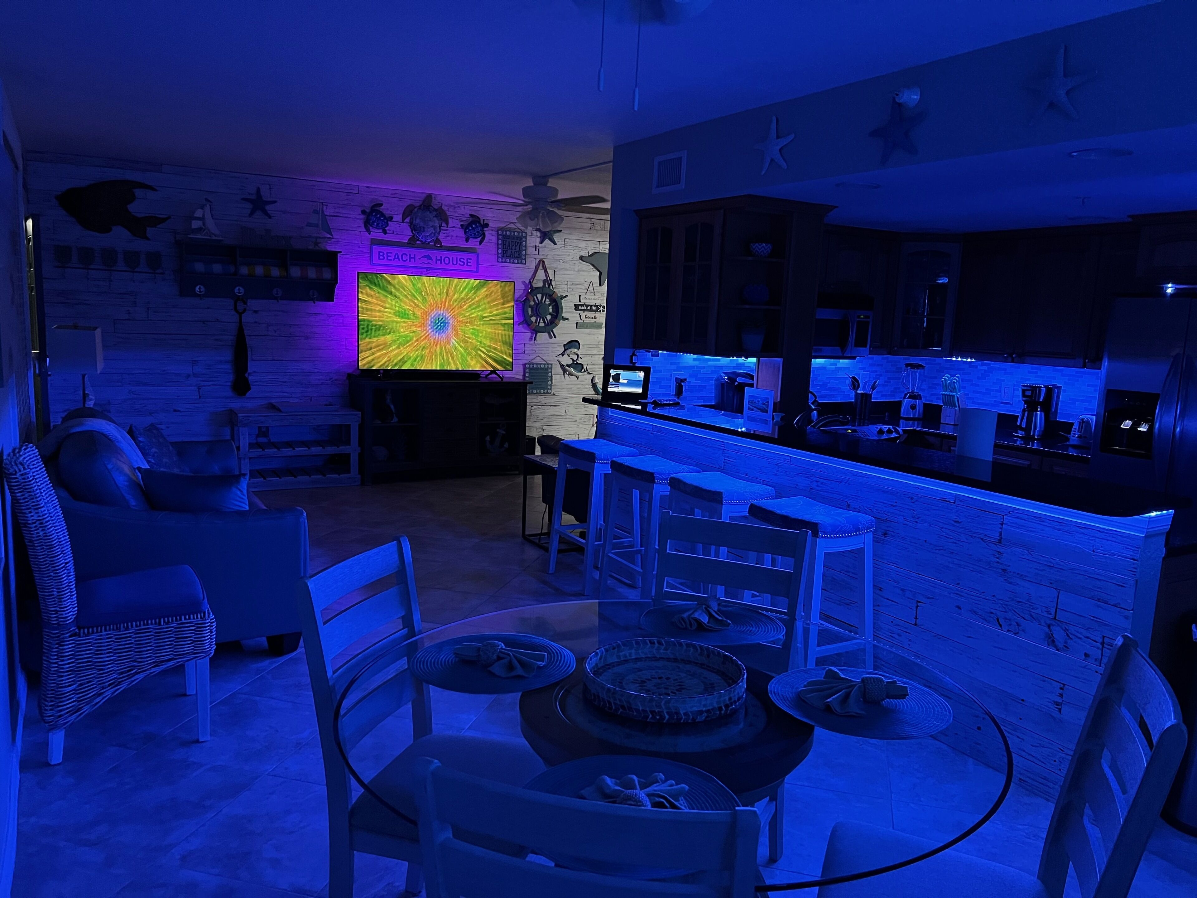 Ett modernt vardagsrum med TV, sittgrupp och ett kök med bardisk.