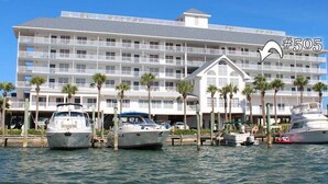 Hotel com vários andares, varandas, barcos atracados em frente e palmeiras.