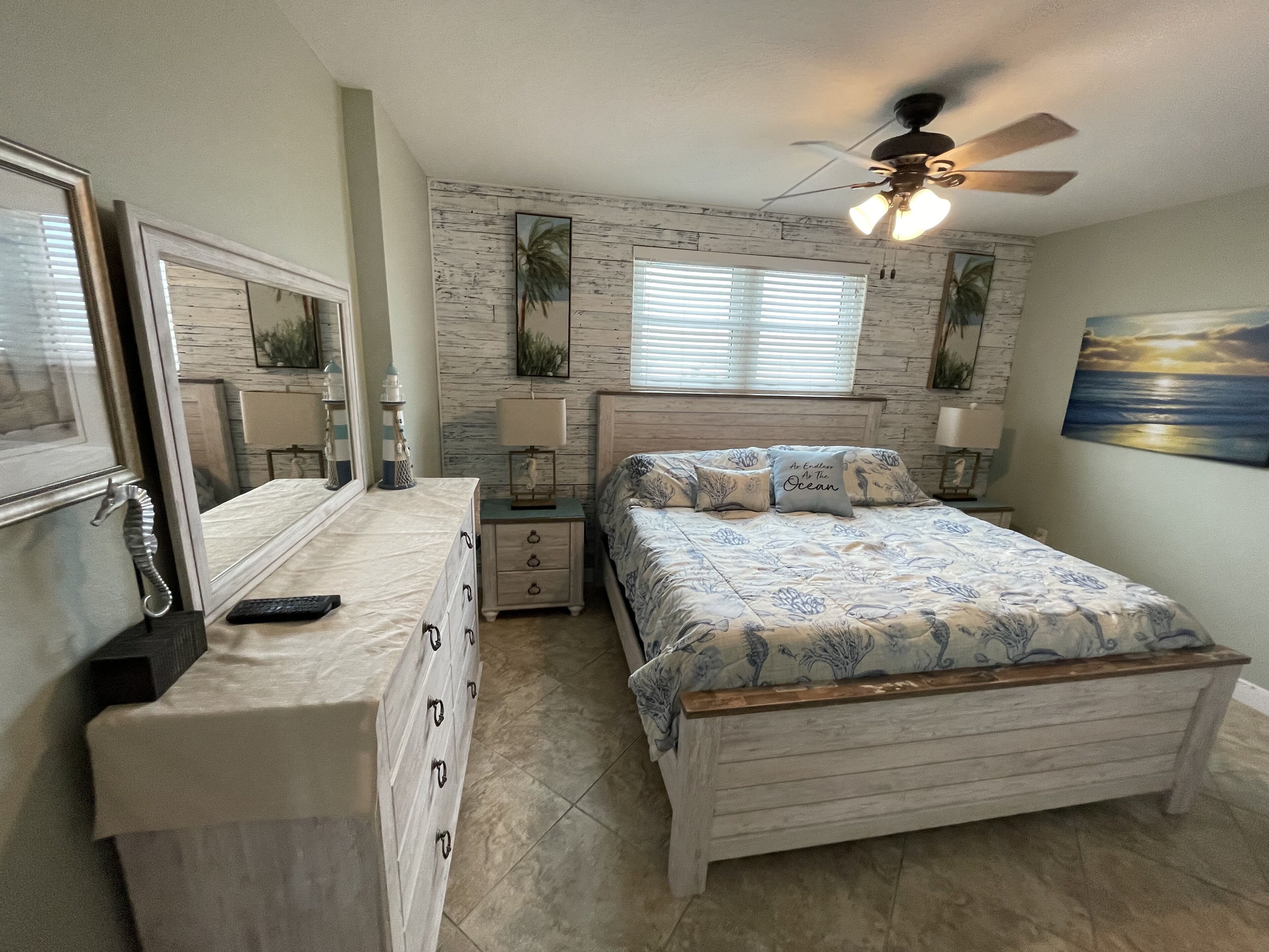A bedroom with a bed, dresser, nightstands, and a ceiling fan.