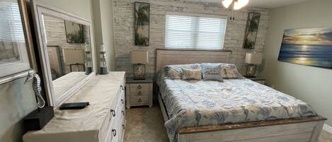 A bedroom with a bed, dresser, nightstands, and a ceiling fan.