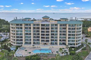 A multi-story hotel with balconies, a swimming pool, and a view of the ocean.