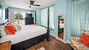 A bedroom with a bed, a ceiling fan, a dresser, and a large mirror.