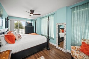 A bedroom with a bed, a ceiling fan, a dresser, and a large mirror.