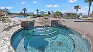 A pool area with multiple pools, lounge chairs, and palm trees.
