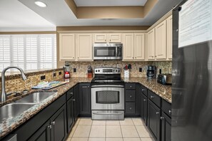 A modern kitchen with a stainless steel refrigerator, double oven, microwave, and granite countertops.