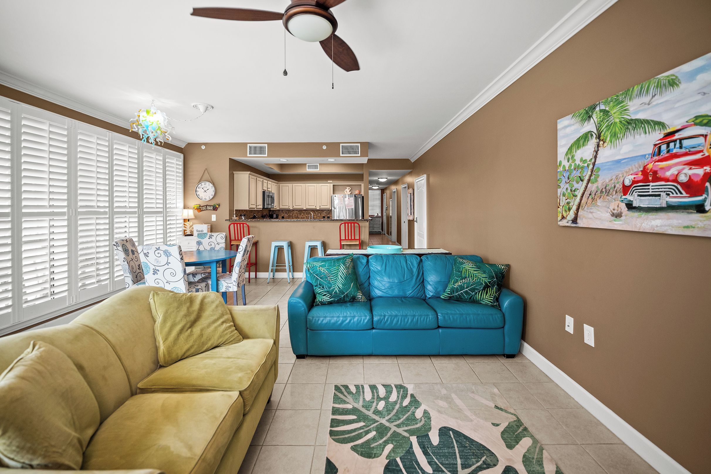 A living room with a blue sofa, a yellow armchair, and a ceiling fan.