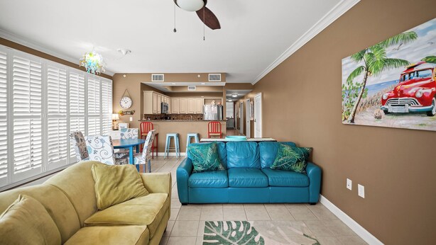 A living room with a blue sofa, a yellow armchair, and a ceiling fan.