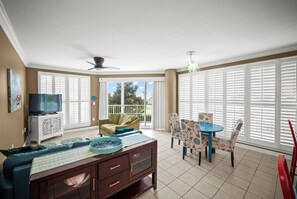 A spacious living room with a television, sofa, dining table, and chairs.