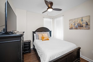 A bedroom with a bed, a ceiling fan, a painting, and a television on a stand. - Stunning 3BR Gulf-View Condo Ground-Floor (Gulf Shores)