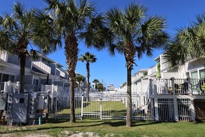 A gated residential area with palm trees, white fences, and houses with balconies. - PEACEFUL EASY FEEELING OFFERS GULF VIEWS & STEPS FROM BEACH! COMMUNITY POOL! (Mexico Beach)