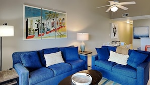 Una sala de estar con dos sofás azules, una mesa de centro y un cuadro de Florida en la pared.