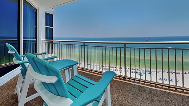 Ein Balkon mit türkisfarbenen Stühlen und Blick auf das Meer.