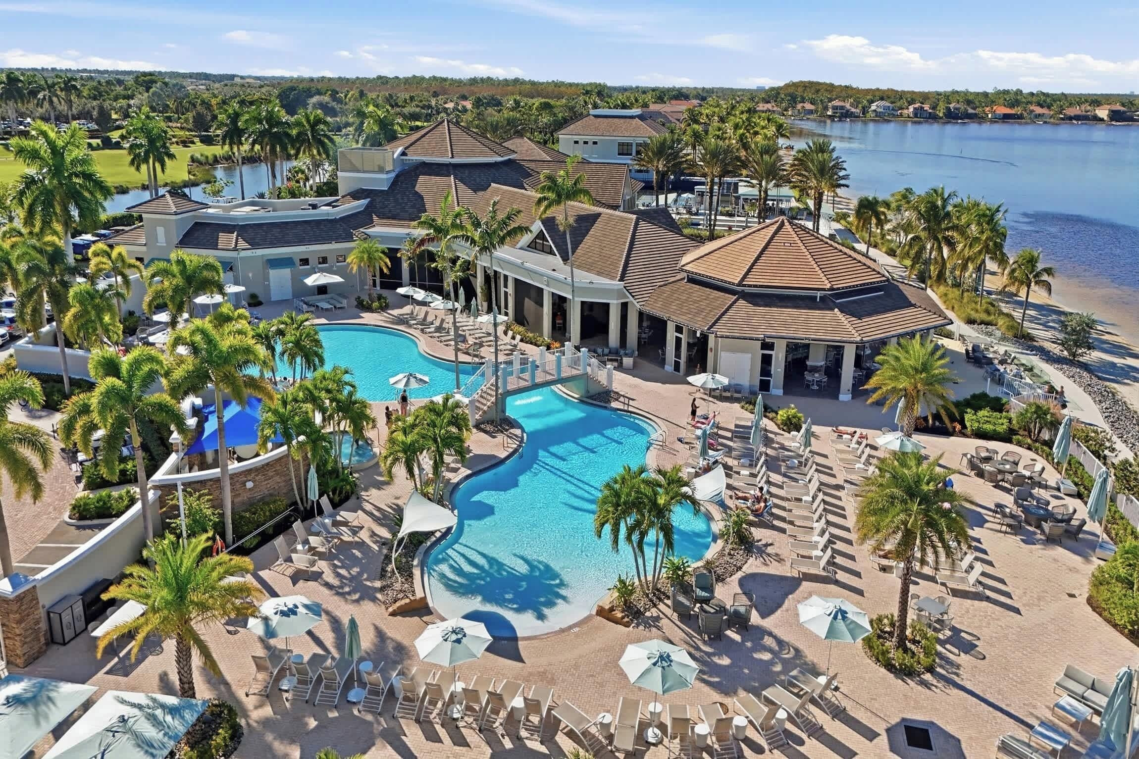 Un resort con varias piscinas, palmeras y vista a un lago.