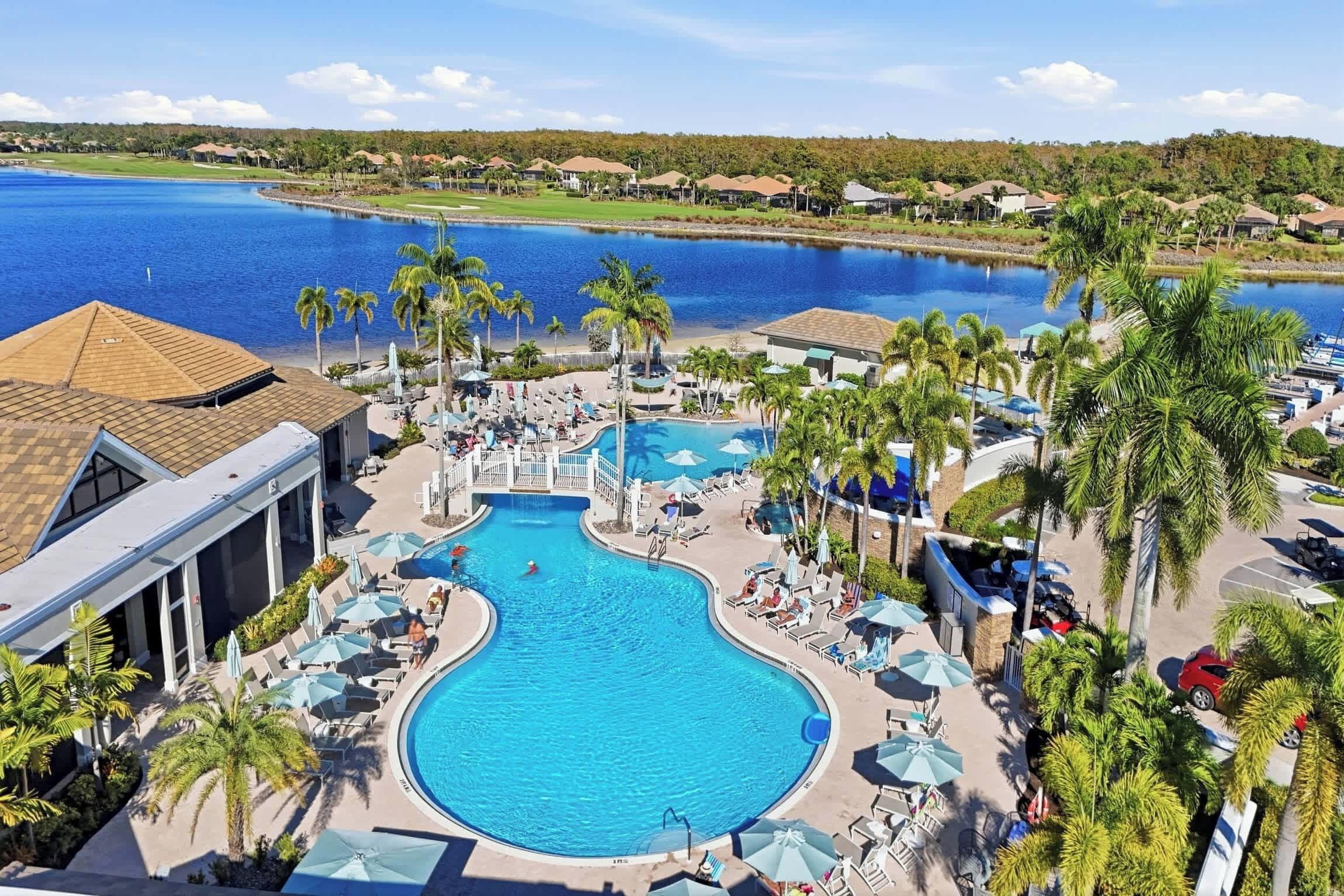 Un resort con una amplia piscina central, varias piscinas más pequeñas y un campo de golf al fondo.