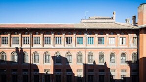 Un edifici gran i antic, amb diverses finestres d'arc i façana de maó vermell.
