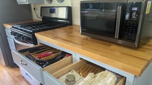 Una cocina con microondas, estufa y cajones.