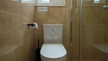 Un baño con inodoro, bidé y cabina de ducha de vidrio.