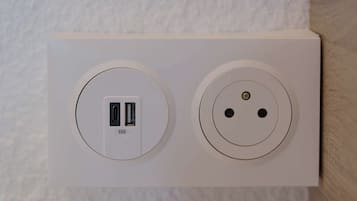Un enchufe blanco con dos puertos USB y una toma de corriente estándar.