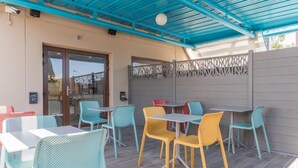An outdoor patio area with tables and chairs, a covered seating area, and a decorative fence. - Kyriad ECO - Toulon Ouest La Seyne sur Mer (La Seyne-sur-Mer)