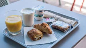 A tray with a glass of orange juice, a cup of milk, a croissant, and a package of biscuits on a table. - Kyriad ECO - Toulon Ouest La Seyne sur Mer (La Seyne-sur-Mer)