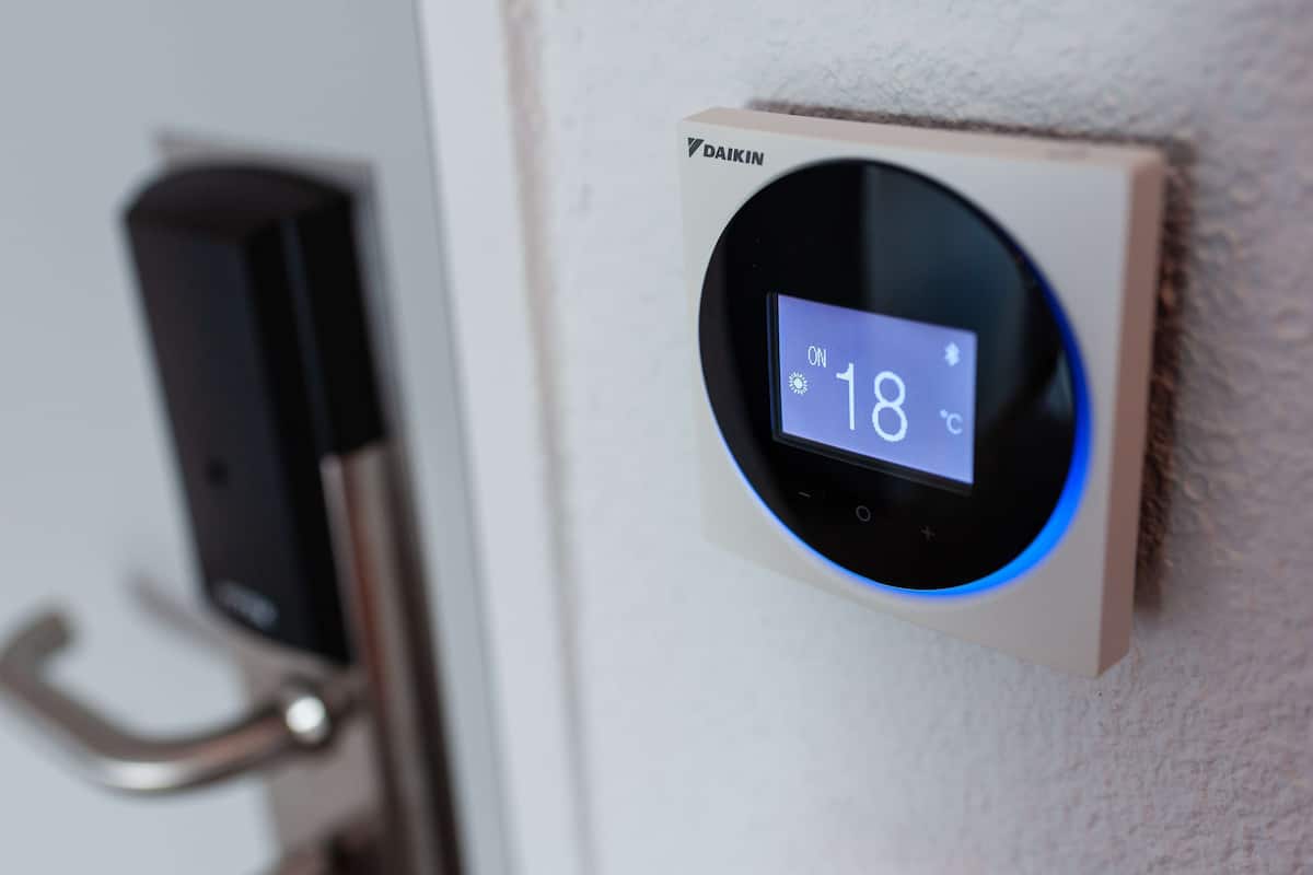A thermostat displaying 18°C, a door handle, and a speaker on a wall.