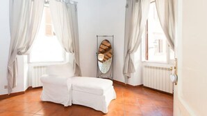 Una habitación con un banco blanco, un radiador y una ventana con cortinas.
