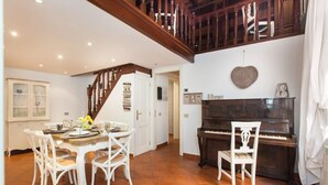 Un comedor con una escalera de madera, un piano y una decoración con forma de corazón en la pared.