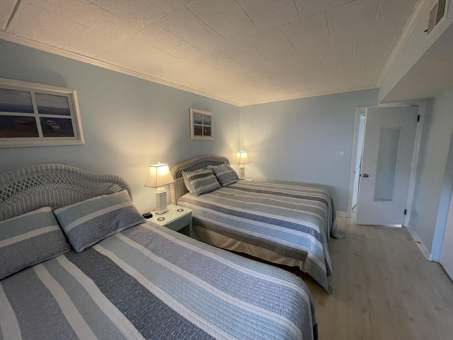 Une chambre à coucher avec deux lits, chacun étant agrémenté de draps à rayures et de lampes de chevet.