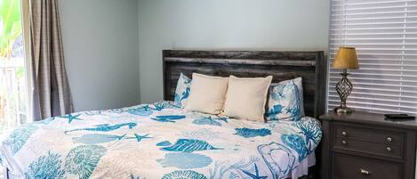 A bedroom with a bed, nightstand, and window with blinds.